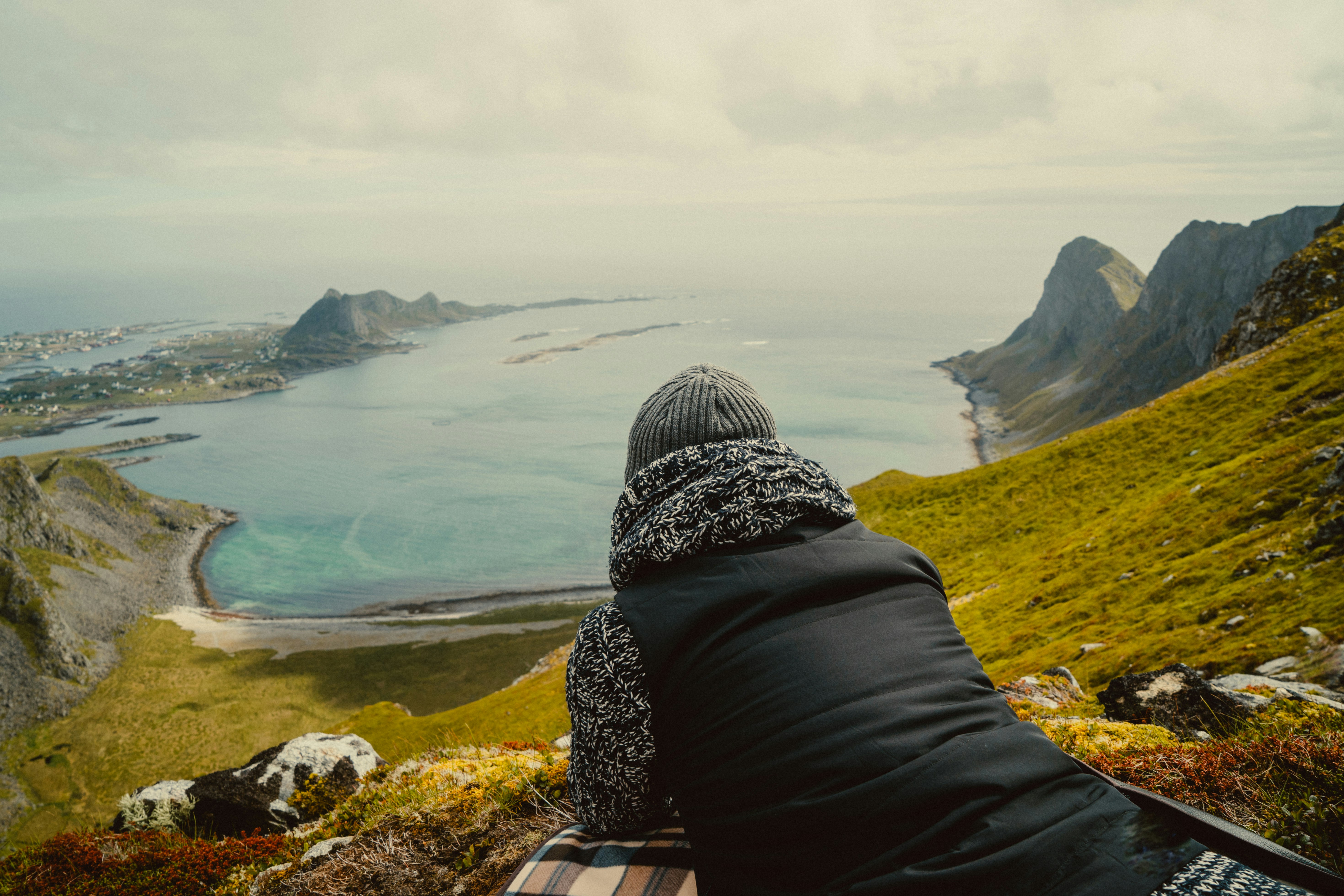 person in black and white hijab sitting on brown rock near body of water during daytime