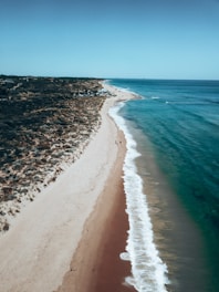 A serene coastal view of Tenerife with a calm beach and nearby hotels.