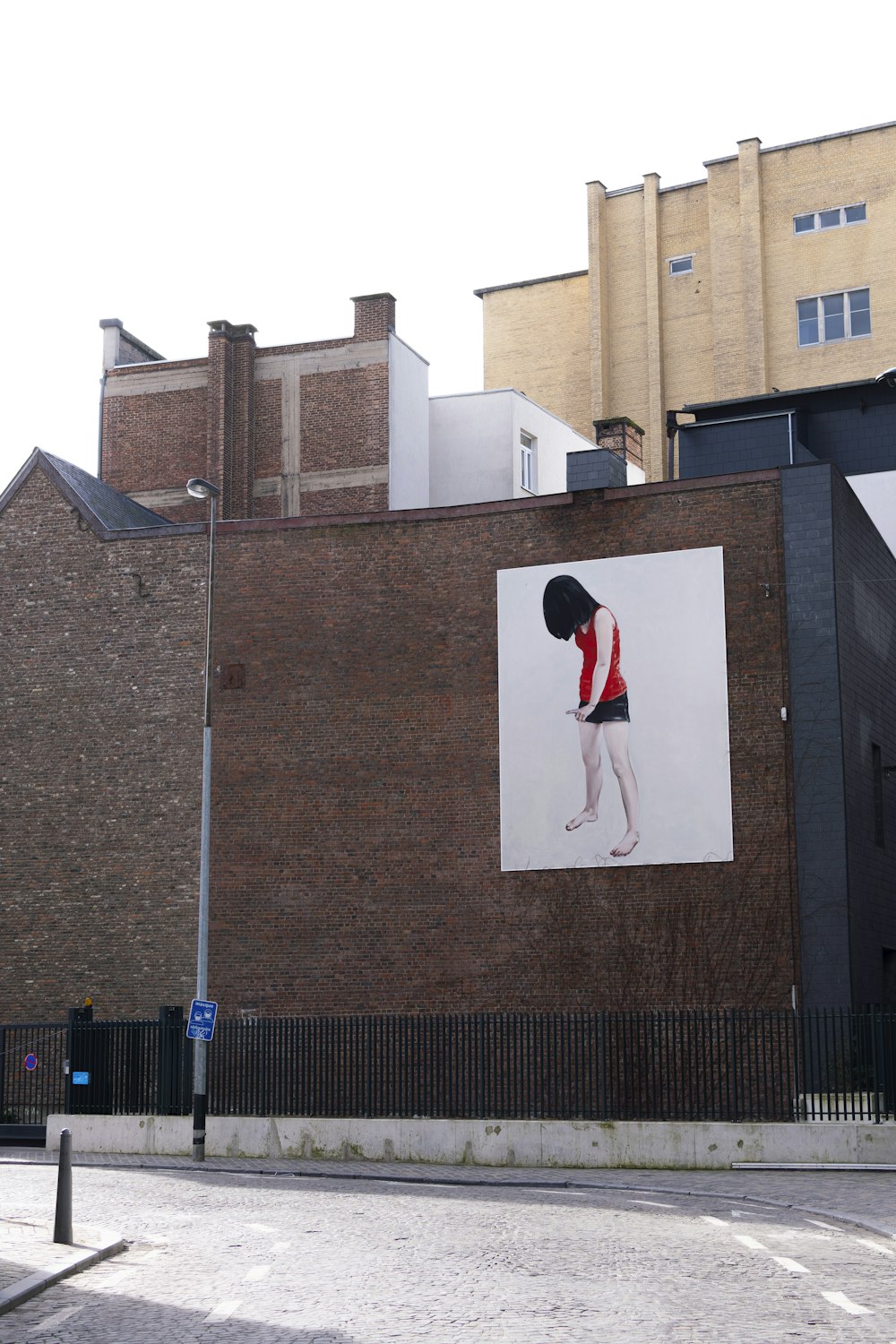昼間、灰色のコンクリートの建物の上に立つ赤と黒のジャケットを着た男性