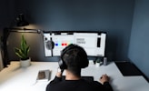 man in black shirt sitting in front of computer
