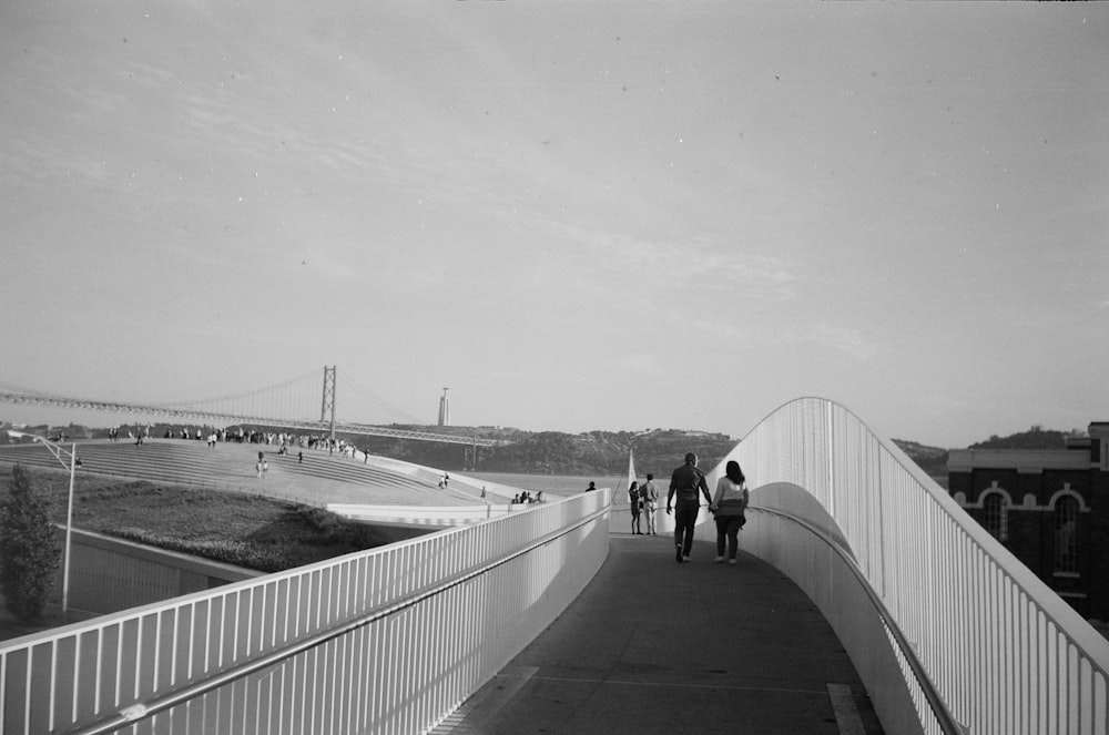grayscale photo of people walking on bridge
