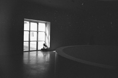 A thoughtful person sitting alone in a dimly lit room, reflecting deeply.