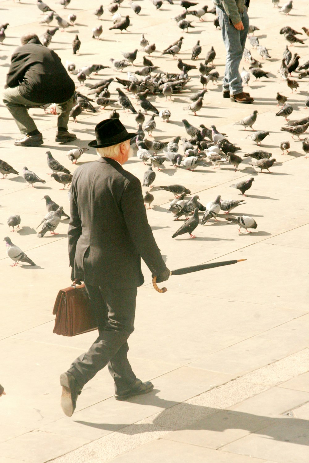 man in gray suit jacket and brown pants walking on white floor tiles