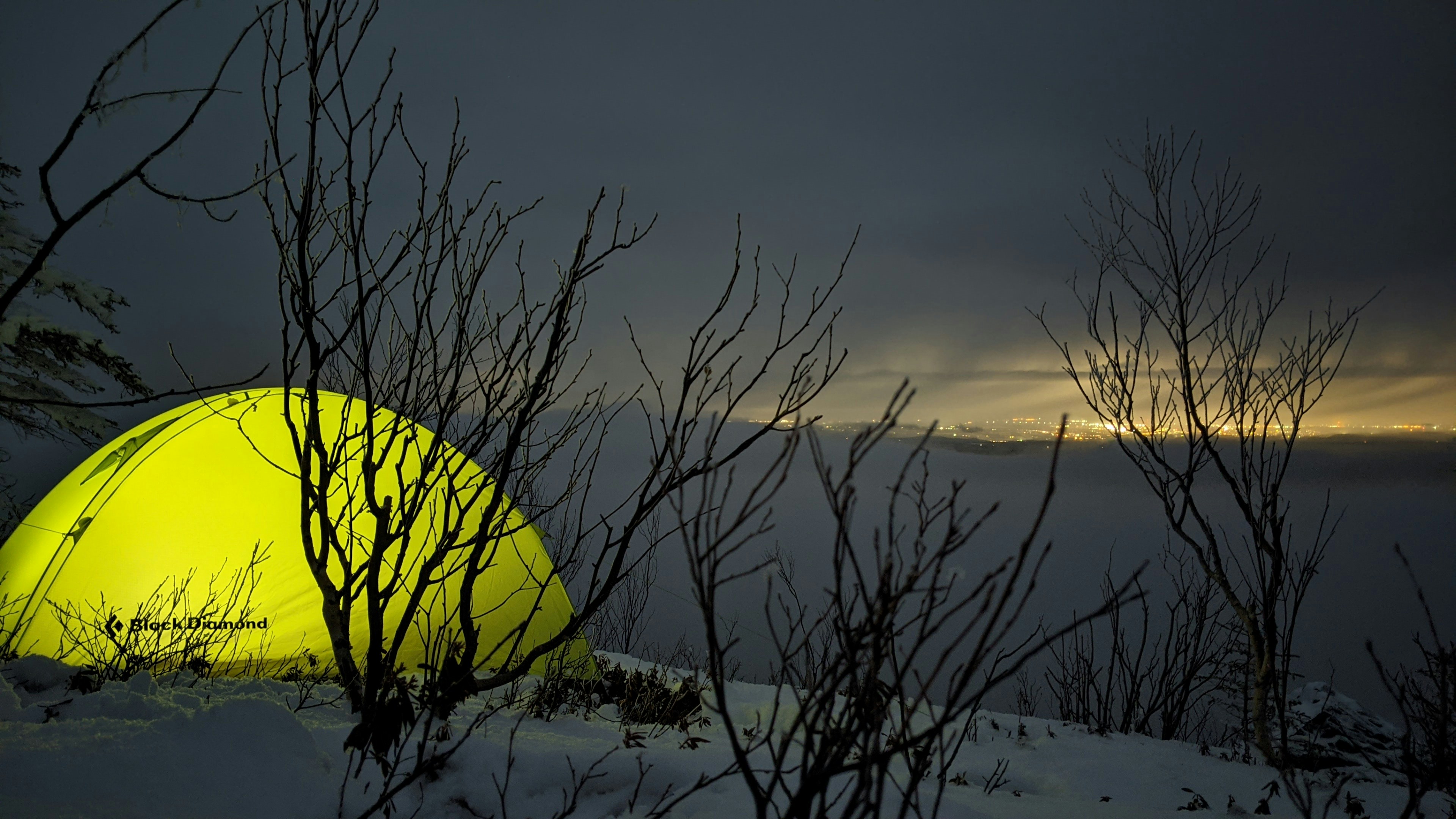 Arktisk vinterfestival med telt og lysdekorasjoner i snødekt landskap om natten