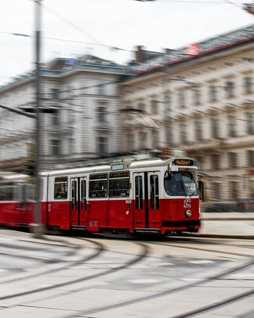 red tram on road near building during daytime