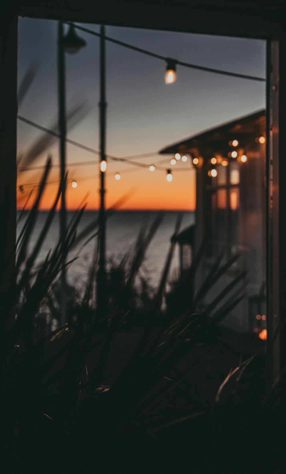 silhouette of fence near body of water during sunset