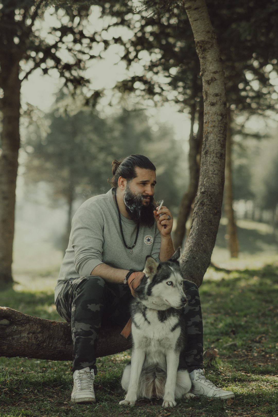 man in gray jacket holding black and white dog