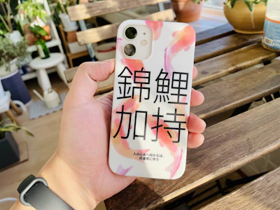 A smiling young Indonesian learner practicing Japanese on a smartphone in a minimalist room.