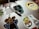 A collection of colorful cartoon character stickers is placed on a silver laptop surface. An assortment of stickers features animated characters and a charging cable draped over the laptop.