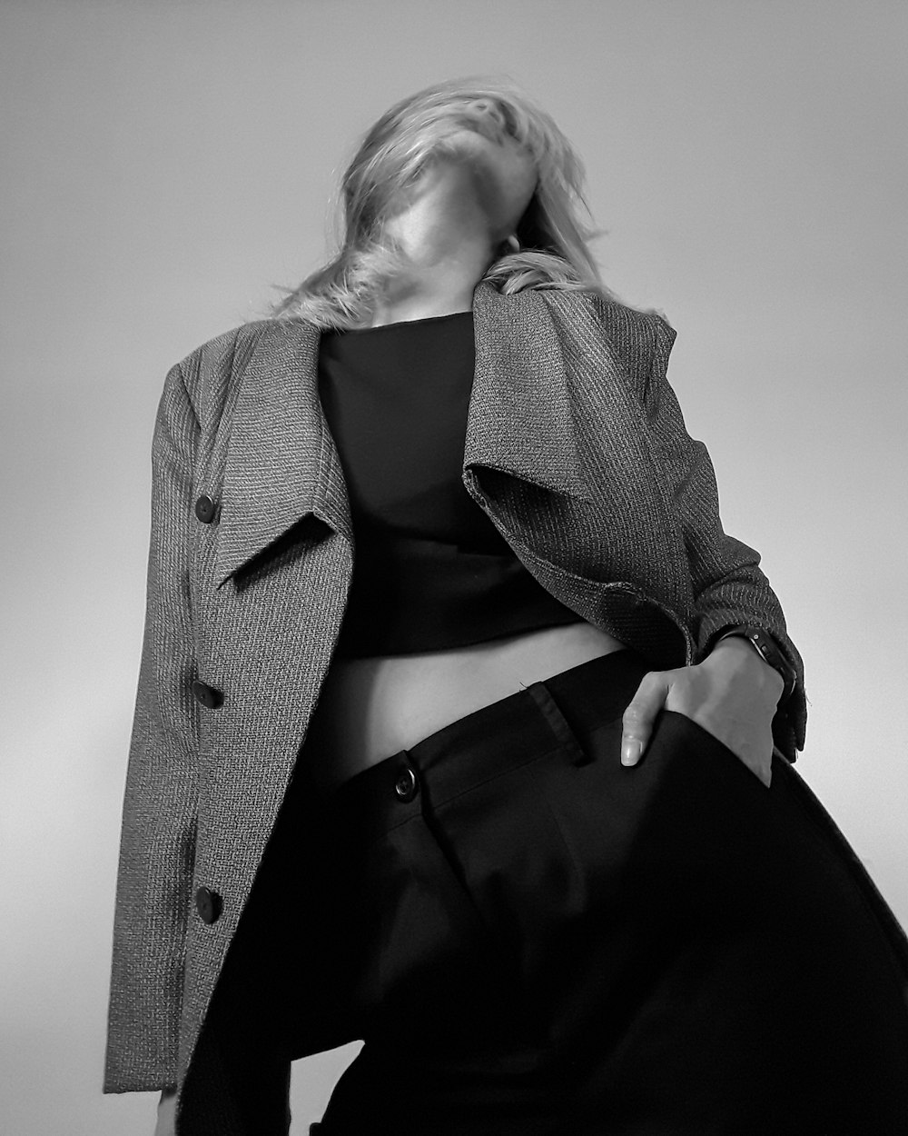 Monochrome editorial portrait of a model in a structured grey coat