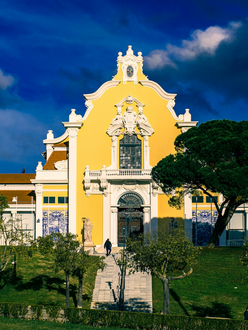 yellow concrete building near green trees under blue sky during daytime