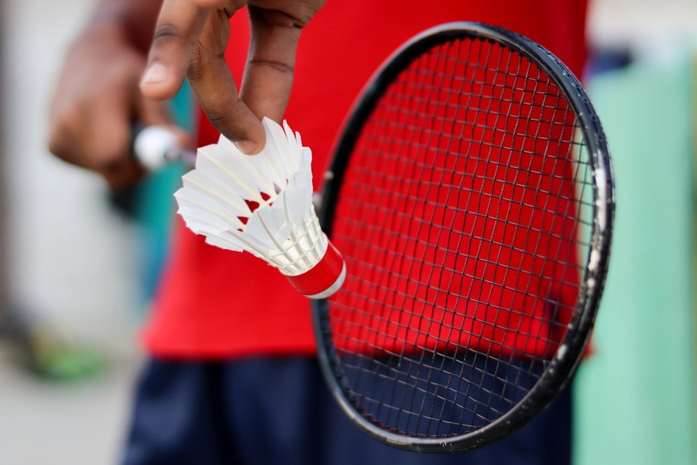 persona sosteniendo raqueta de tenis roja y negra