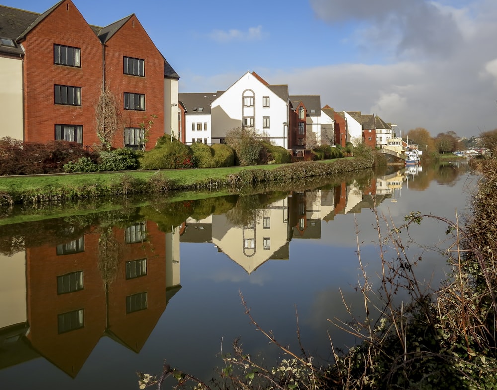 brown and white concrete buildings beside body of water under blue sky during daytime