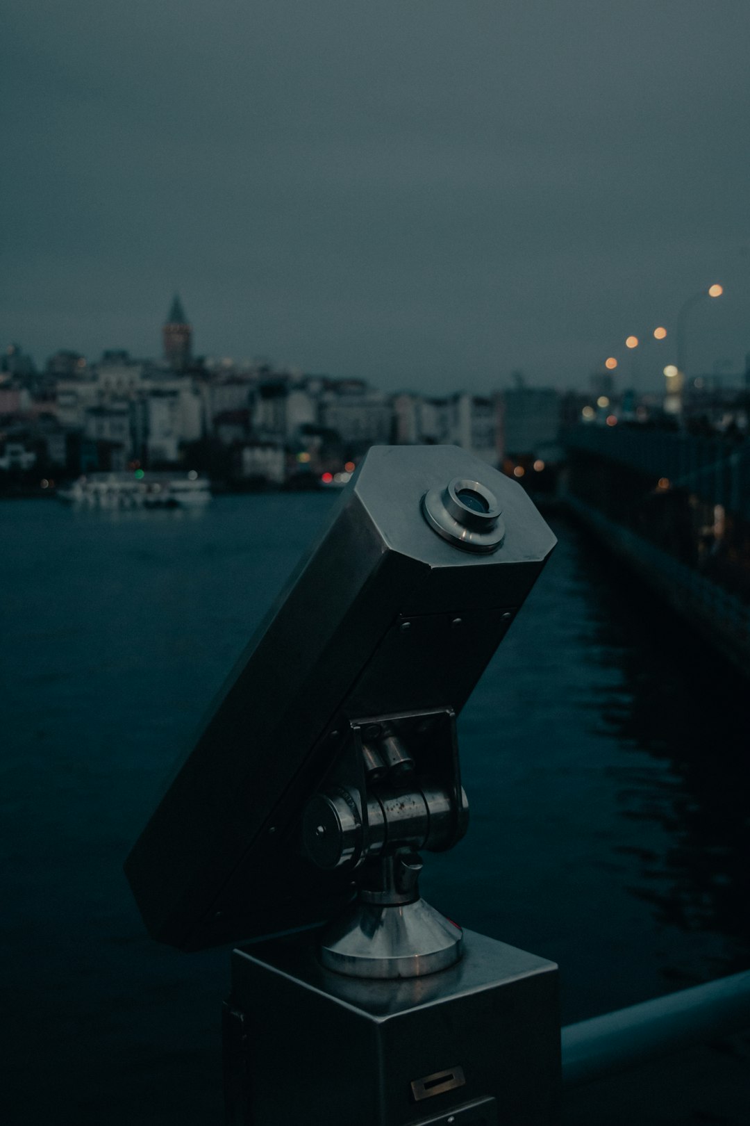 black telescope in front of city buildings during night time