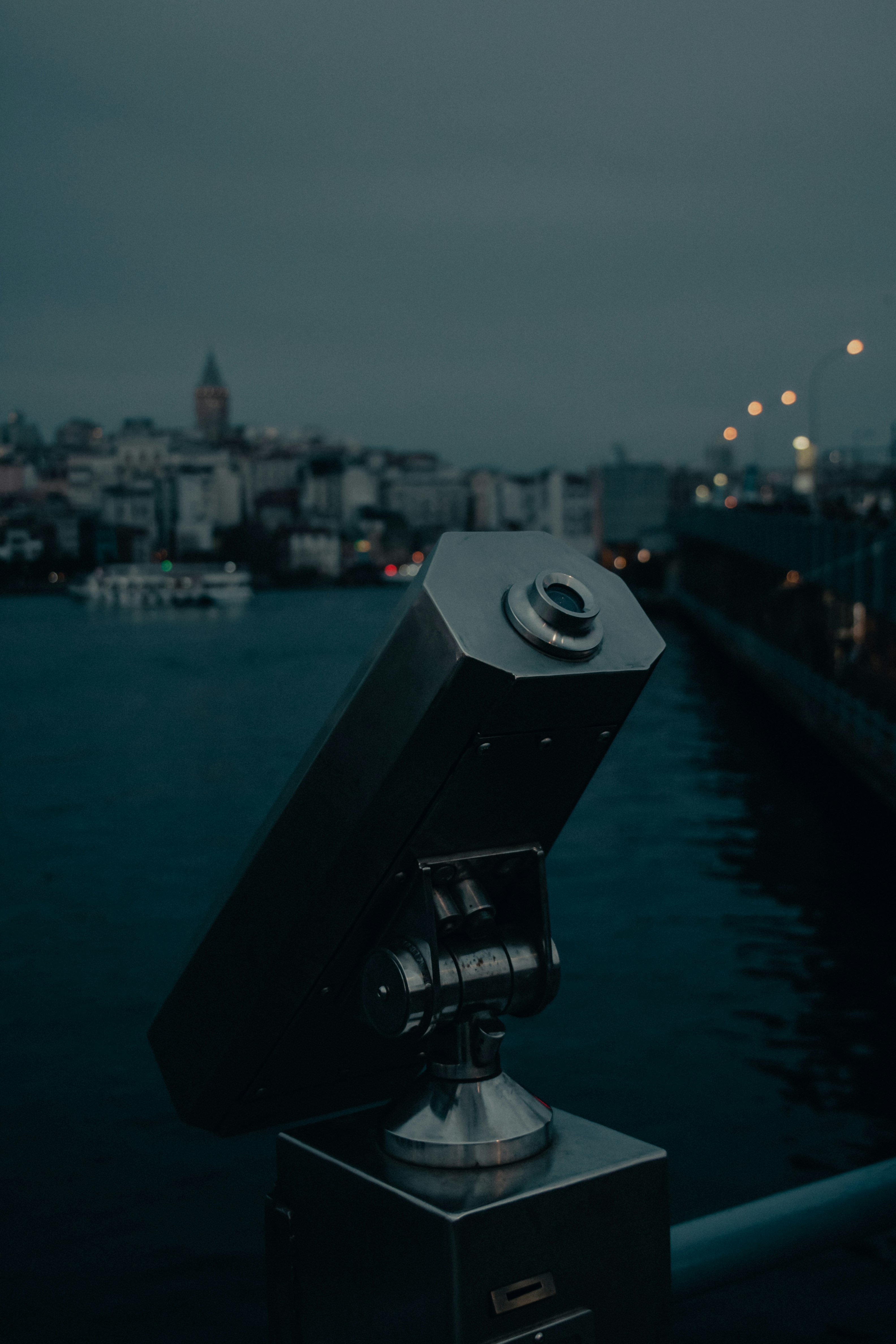 black telescope in front of city buildings during night time