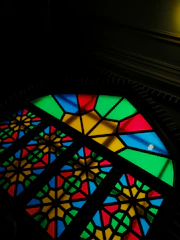 A colorful window painting featuring floral and geometric patterns glowing in natural light.