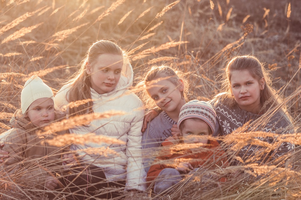 낮에 갈색 마른 풀밭에 누워 있는 3명의 소녀
