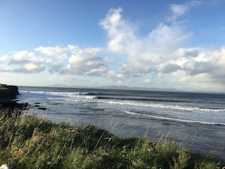 Soft waves gently rolling onto a rocky shore with distant mountains in view.