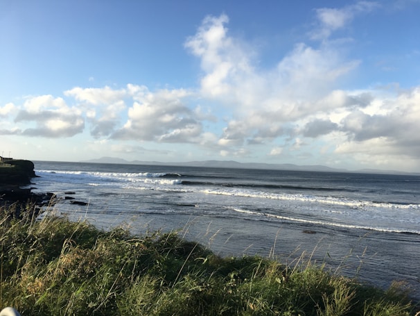 Soft waves gently rolling onto a rocky shore with distant mountains in view.