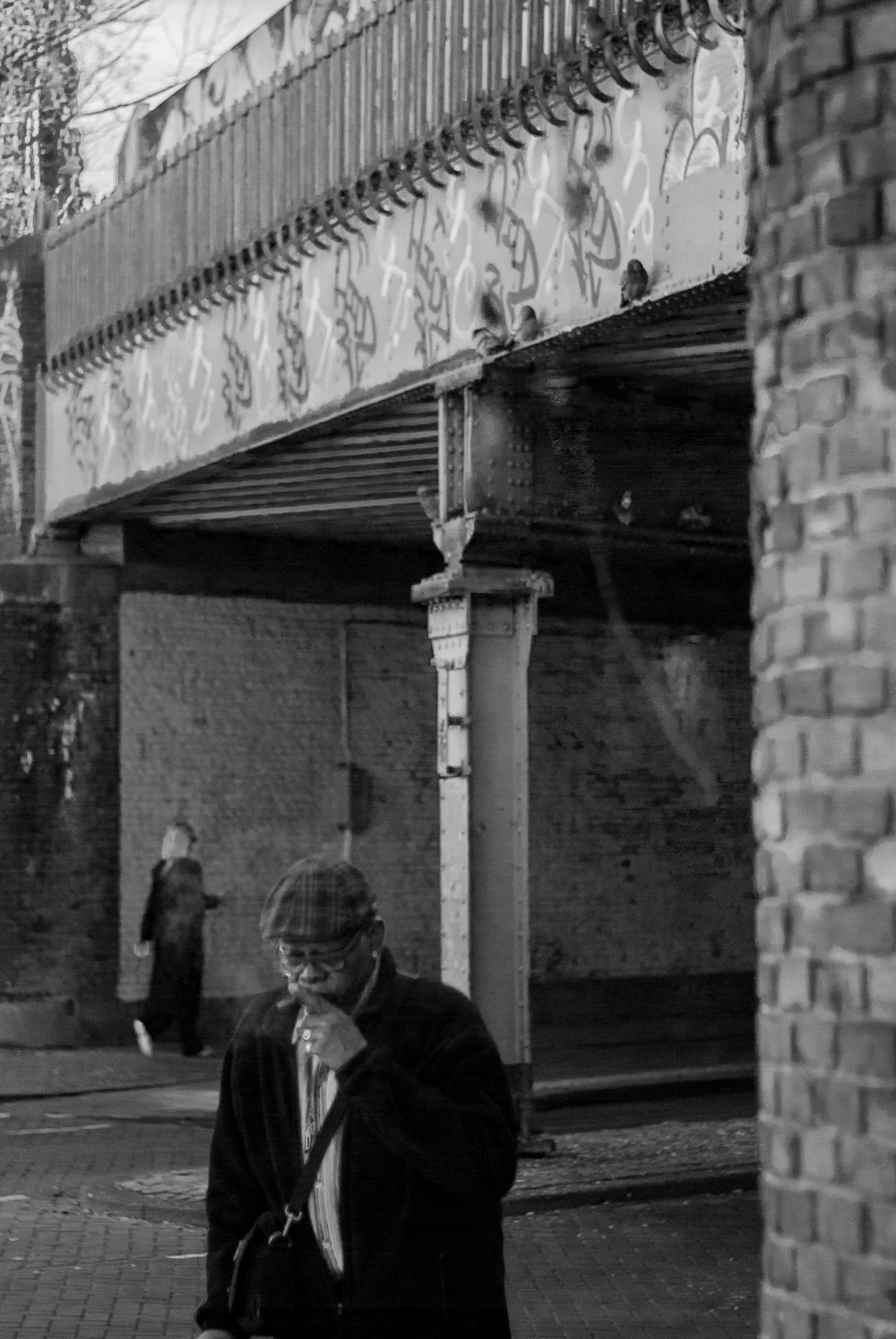 Foto in scala di grigi di uomo e donna in piedi vicino al muro di cemento