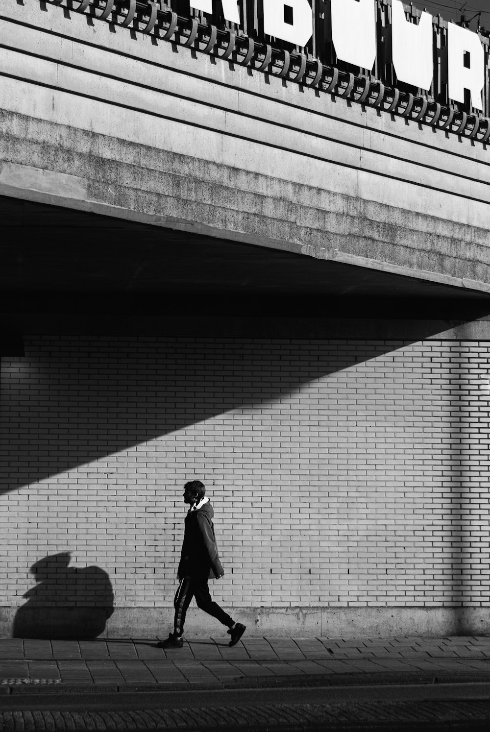 uomo in abito nero in piedi sul muro di cemento grigio