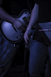 person playing black electric guitar