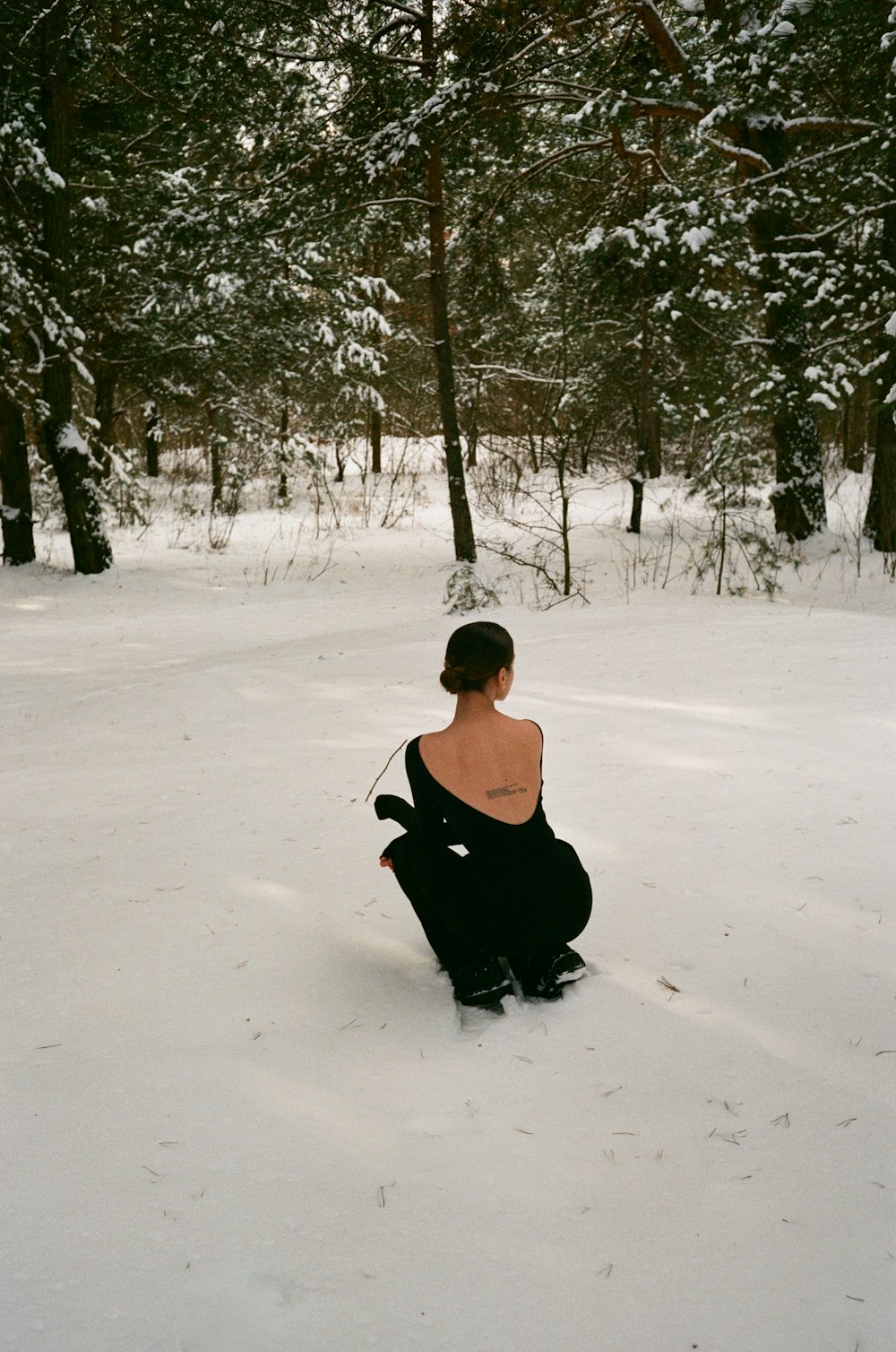woman in black tank top and black pants sitting on snow covered ground during daytime