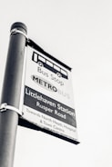 A black and white image of a bus stop sign for Littlehaven Station on Rusper Road. It provides directions towards North Heath, Hospital, and Town Centre.