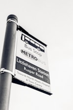 A black and white image of a bus stop sign for Littlehaven Station on Rusper Road. It provides directions towards North Heath, Hospital, and Town Centre.