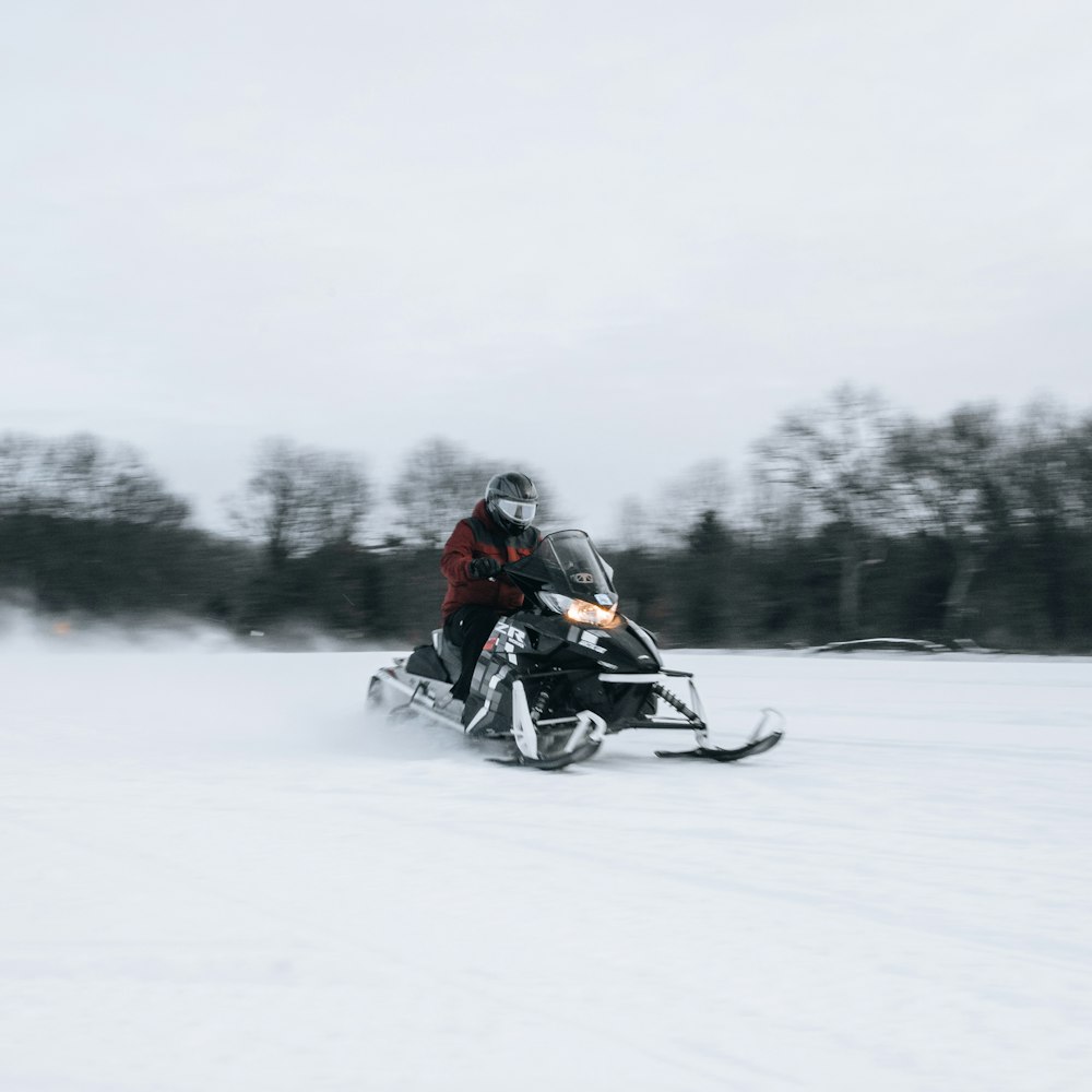 man riding on black motorcycle on snow covered field during daytime