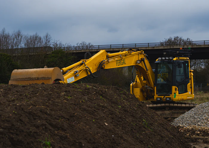 Excavator grading dirt on active construction site