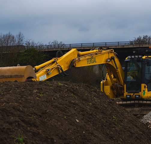 yellow excavator on brown soil under white clouds during daytime