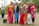 A group of women wearing colorful traditional eastern dresses smiling outdoors.