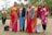 A group of women wearing colorful traditional eastern dresses smiling outdoors.