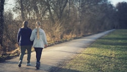 woman in white jacket and black pants walking on road during daytime