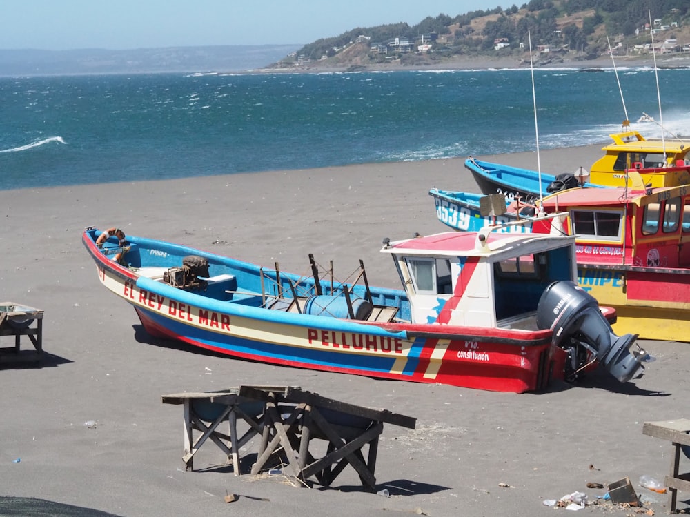 red and blue boat on beach during daytime