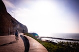 Group of happy travelers biking along a scenic coastal trail with turquoise sea on one side