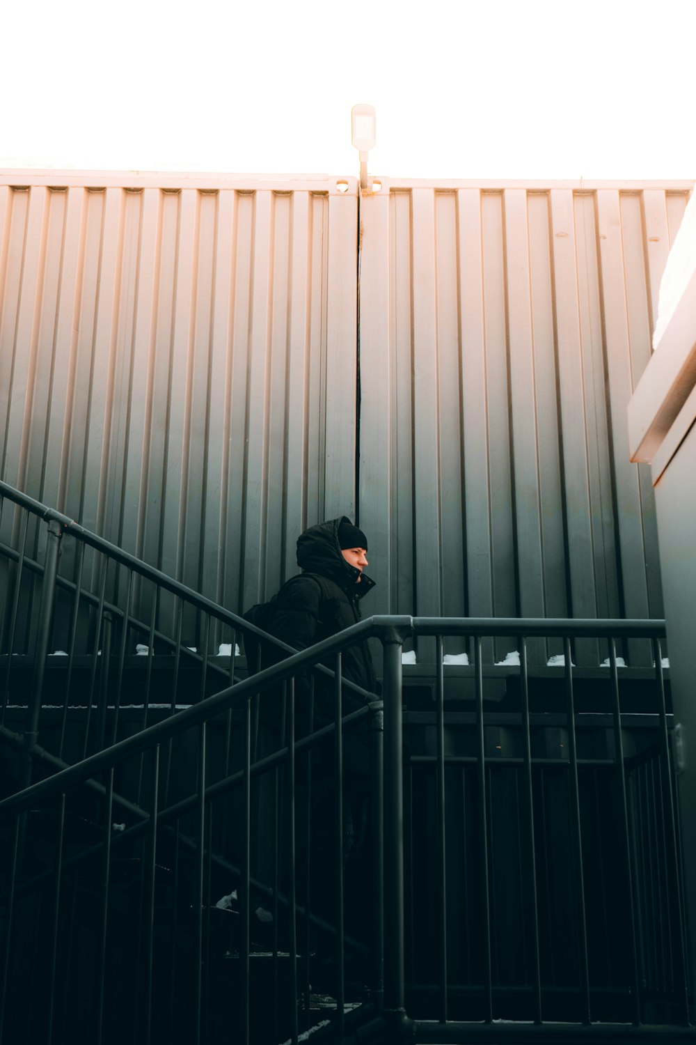 man in black hoodie standing on black metal staircase