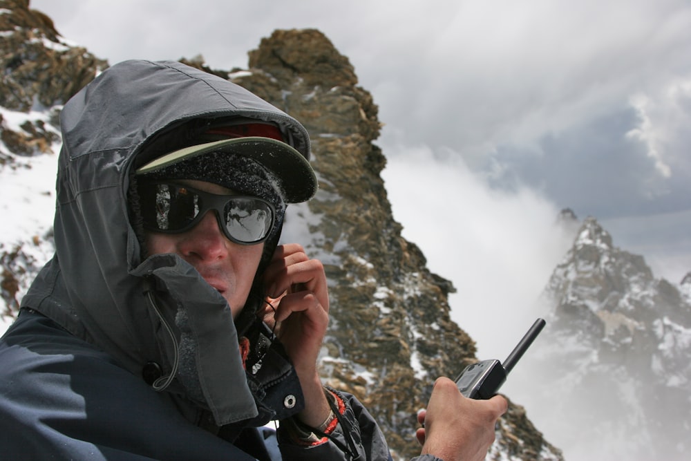 man in black jacket holding black smartphone