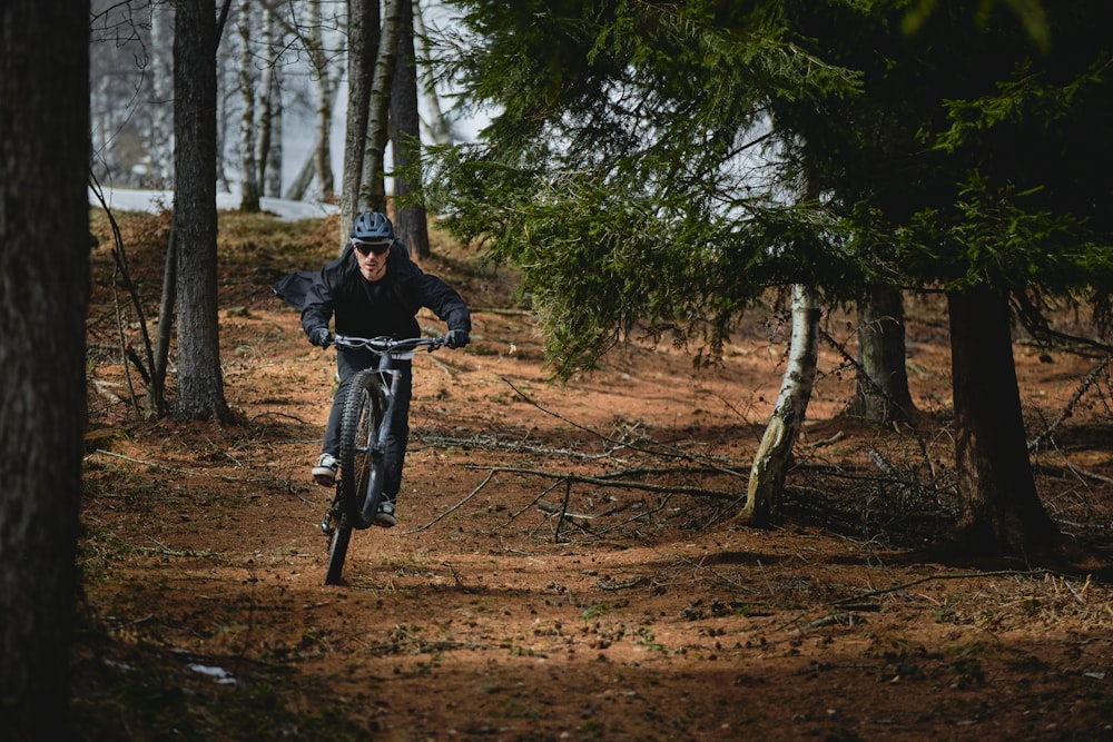 Hombre en chaqueta negra montando en bicicleta en camino de tierra marrón durante el día