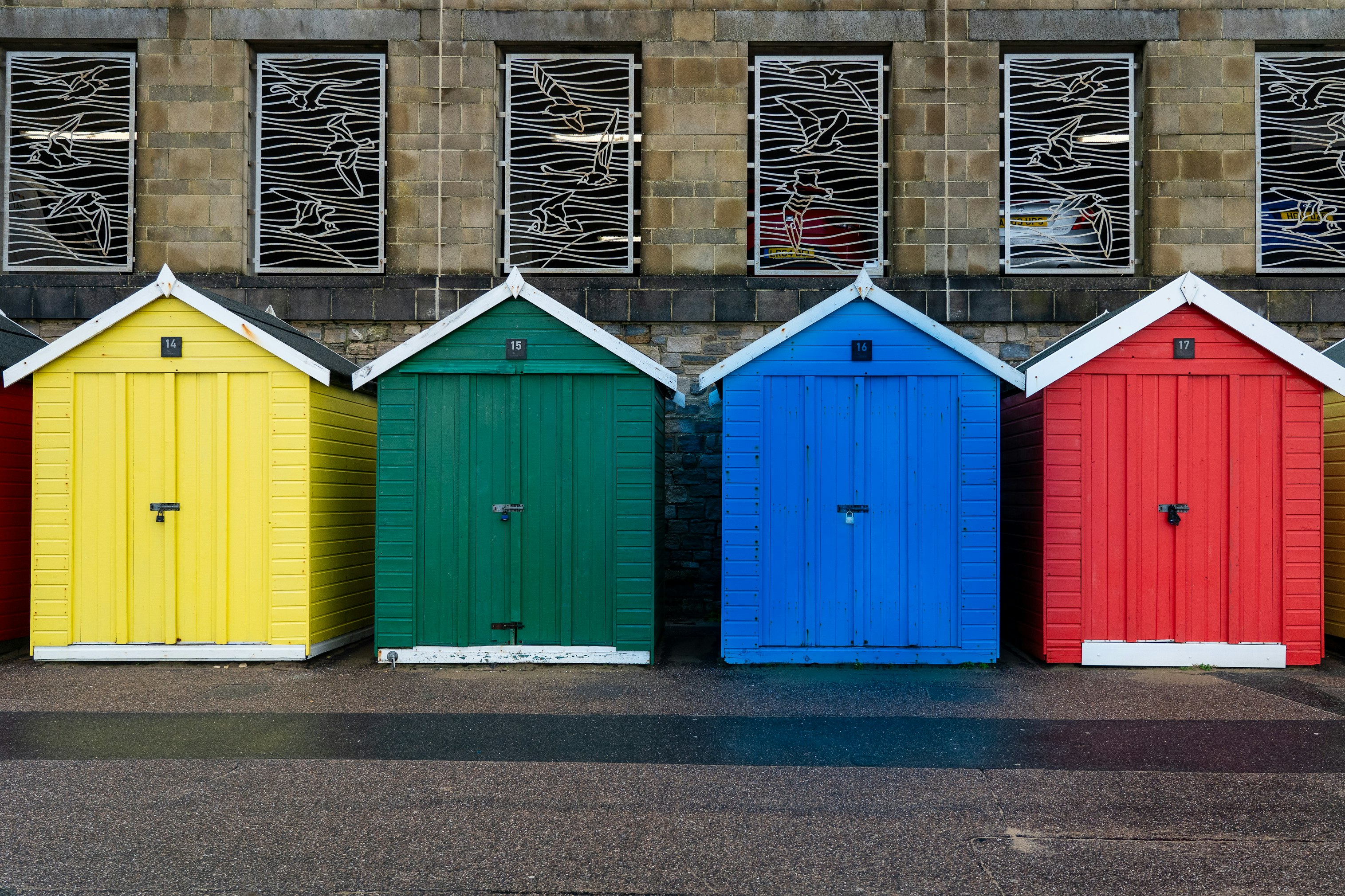 Four beach huts, each painted in the four primary colours, of yellow, green, blue and red.