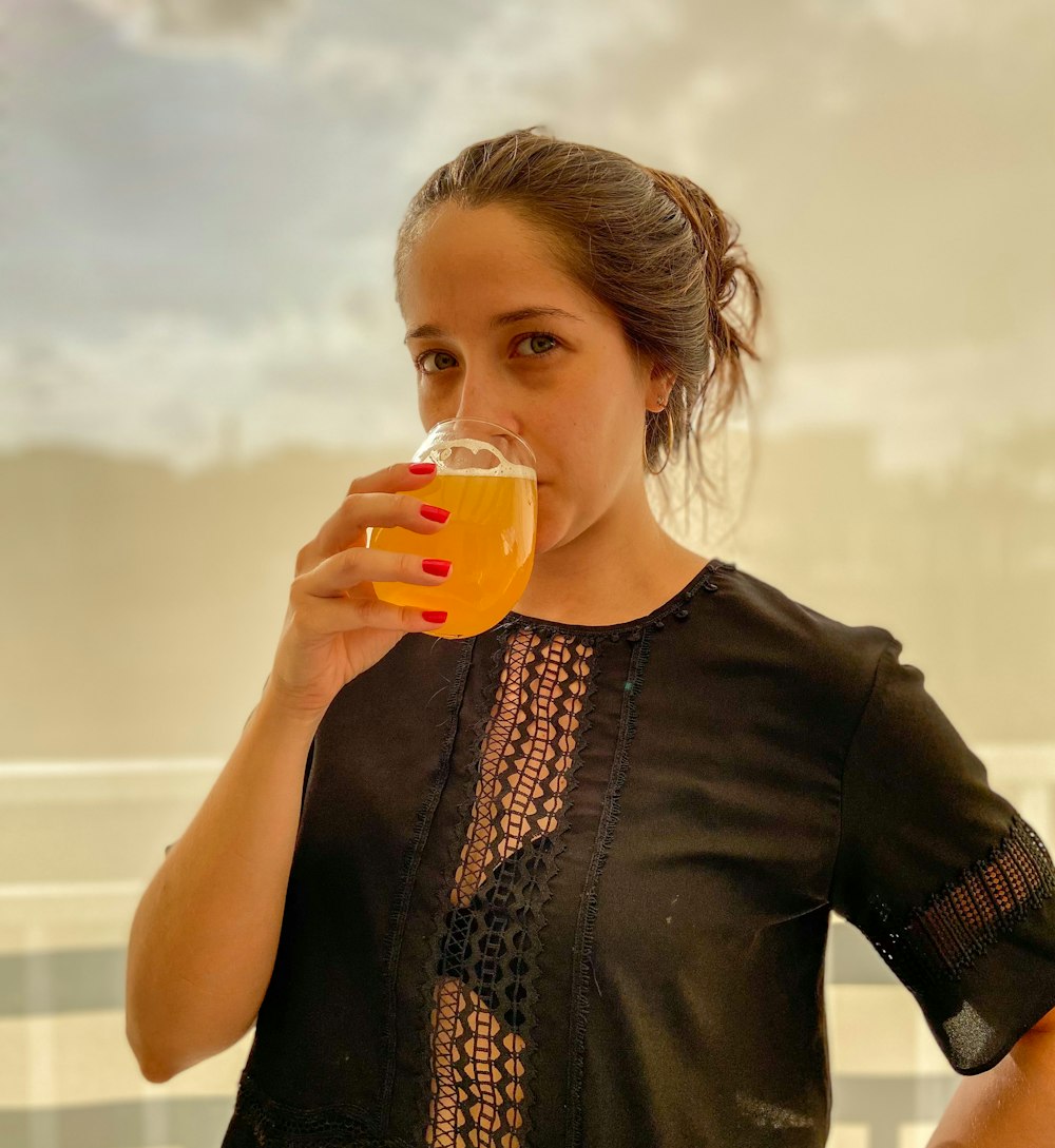 woman in black cardigan drinking from clear glass mug