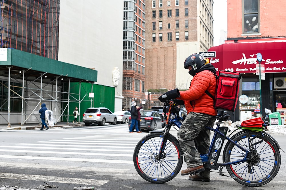 昼間の道路で青いバイクに乗る青いジャケットの男