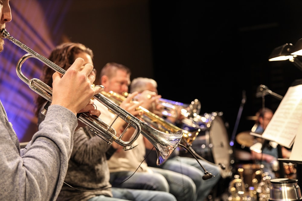 man in gray sweater playing trumpet