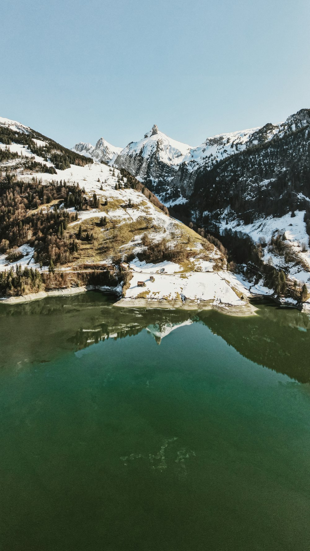 lake in the middle of snow covered mountains