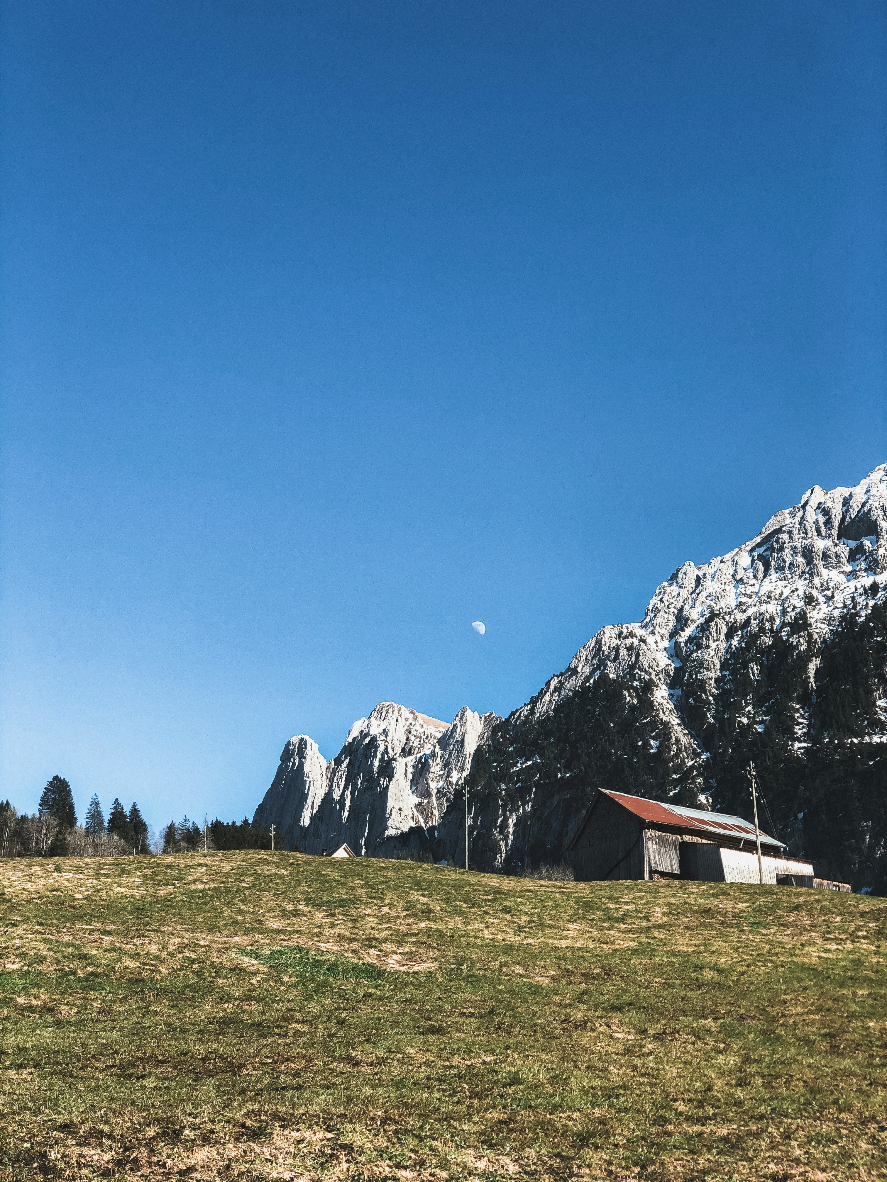 white and brown house on green grass field near gray rocky mountain under blue sky during