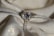 A sparkling diamond ring resting on a textured, shimmering fabric. The ring features a large solitaire diamond set in a prong setting, with smaller diamonds embedded along the band. The fabric underneath is cream-colored with a subtle glitter effect, adding to the overall luxurious ambience.