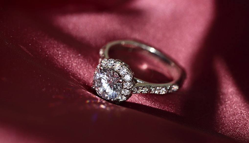 silver diamond ring on red textile