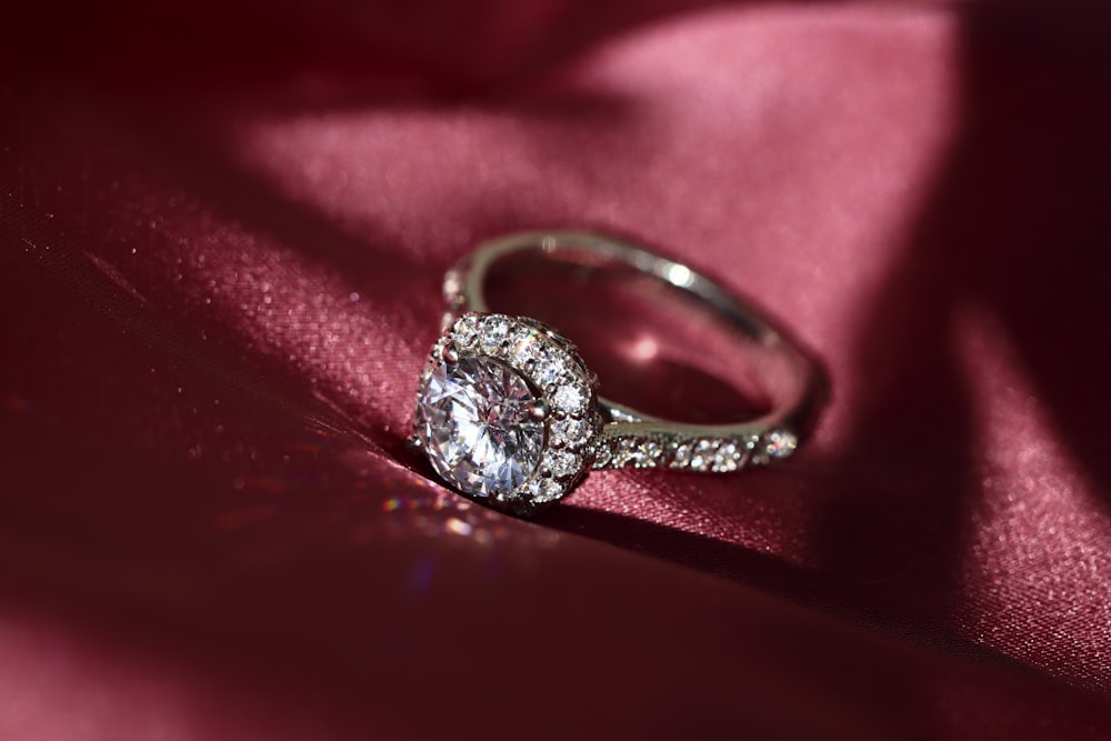 silver diamond ring on red textile