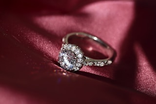 silver diamond ring on red textile